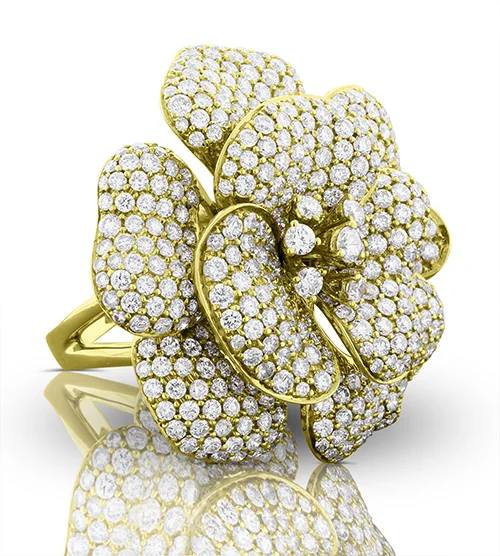 High end jewelry retouching of a gold pavé flower cocktail ring, brightened on white with a mirror reflection